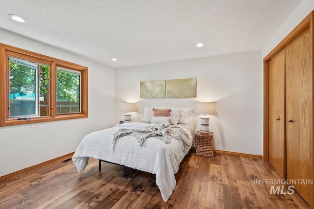 9421 W Rifleman St, Boise, ID 83703 - bedroom featuring baseboards, wood finished floors, recessed lighting, a closet, and a textured ceiling