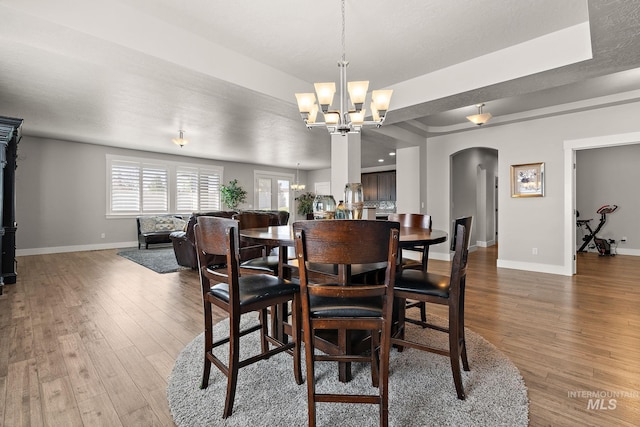 11153 W Brett Dr, Nampa, ID 83686 - dining area featuring arched walkways, baseboards, wood-type flooring, and a chandelier