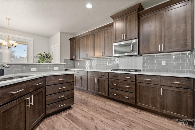 11153 W Brett Dr, Nampa, ID 83686 - kitchen featuring stainless steel appliances, a sink, a chandelier, light wood-style floors, and dark brown cabinets