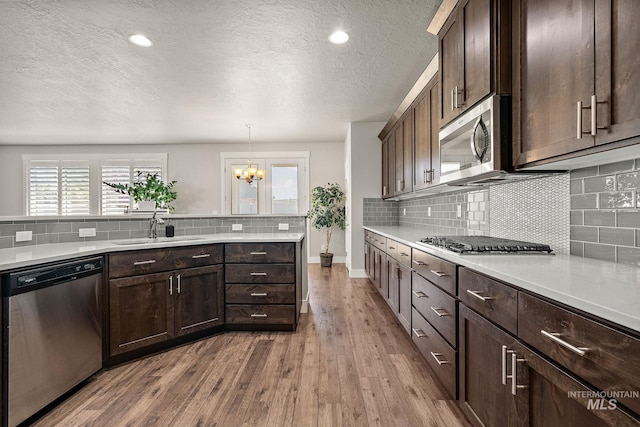 11153 W Brett Dr, Nampa, ID 83686 - kitchen with stainless steel appliances, a sink, dark wood-type flooring, tasteful backsplash, and light countertops