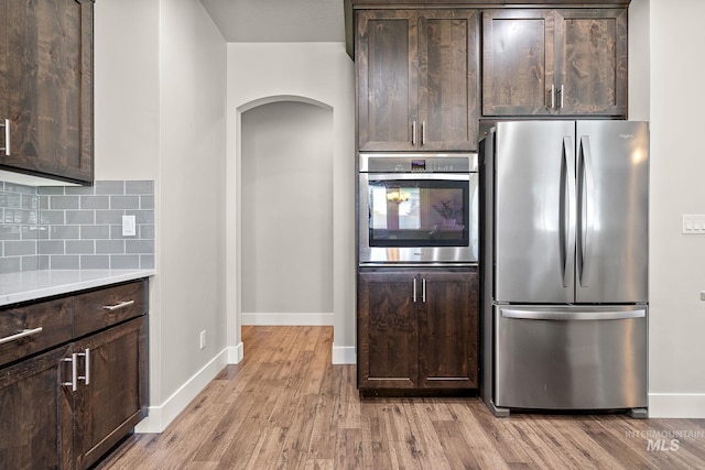 11153 W Brett Dr, Nampa, ID 83686 - kitchen with stainless steel appliances, arched walkways, dark brown cabinets, and light wood-type flooring