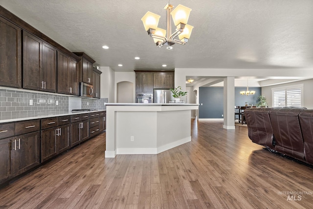 11153 W Brett Dr, Nampa, ID 83686 - kitchen featuring a chandelier, stainless steel appliances, open floor plan, dark brown cabinets, and wood finished floors