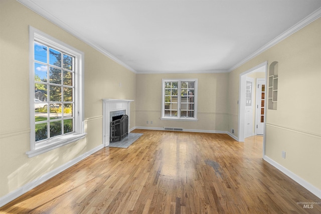 unfurnished living room featuring wood finished floors, baseboards, visible vents, a fireplace with flush hearth, and ornamental molding