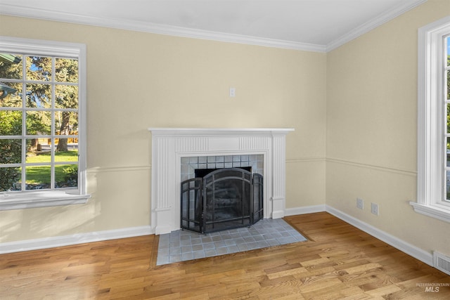 details featuring ornamental molding, wood finished floors, baseboards, and a tile fireplace