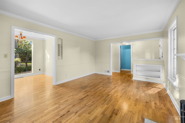 empty room with light wood finished floors, baseboards, and ornamental molding