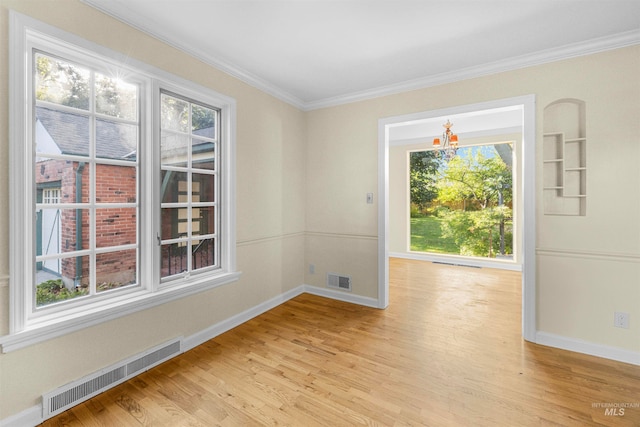 empty room featuring visible vents, baseboards, light wood-style flooring, and crown molding