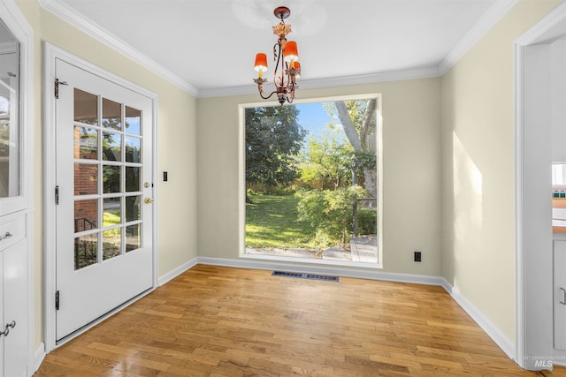 unfurnished dining area featuring visible vents, an inviting chandelier, ornamental molding, and light wood finished floors