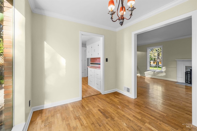 unfurnished dining area with a fireplace with flush hearth, visible vents, light wood-style floors, and ornamental molding