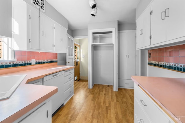 kitchen featuring light wood-style flooring, white cabinetry, light countertops, decorative backsplash, and dishwasher