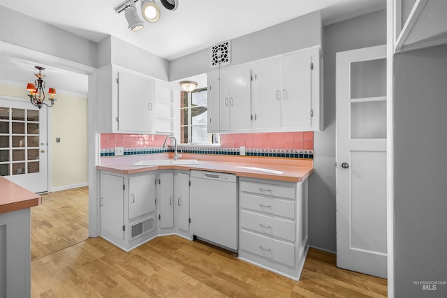 kitchen with a sink, light countertops, white dishwasher, and light wood finished floors