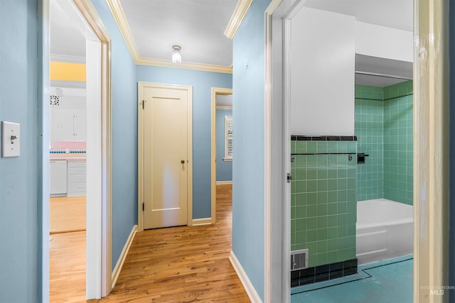 hallway featuring baseboards, wood finished floors, tile walls, and ornamental molding