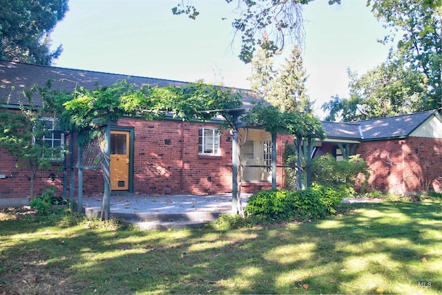 rear view of house featuring a yard, a patio area, brick siding, and a shingled roof