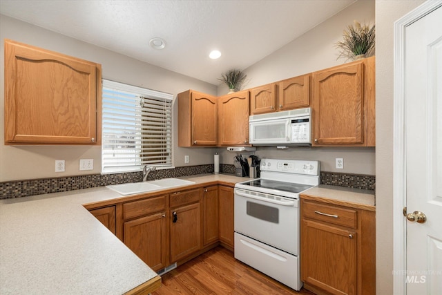 kitchen featuring lofted ceiling, sink, white appliances, and light wood-type flooring