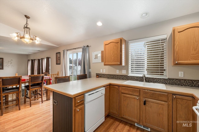 kitchen with sink, dishwasher, hanging light fixtures, kitchen peninsula, and light wood-type flooring