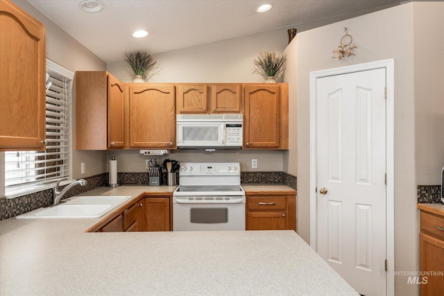 kitchen featuring vaulted ceiling, sink, and white appliances