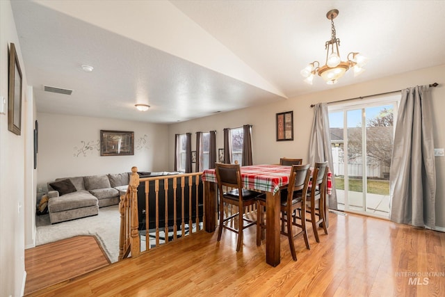 dining room with vaulted ceiling, a chandelier, and light hardwood / wood-style floors