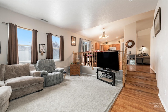 living room with lofted ceiling, a notable chandelier, and light hardwood / wood-style floors