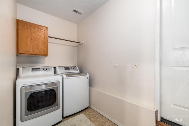 laundry area with cabinets, washing machine and clothes dryer, and a textured ceiling