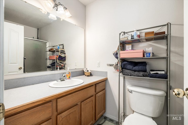 bathroom with vanity, a shower with shower door, and toilet