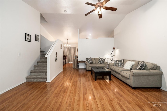 living room featuring ceiling fan with notable chandelier, lofted ceiling, and hardwood / wood-style floors