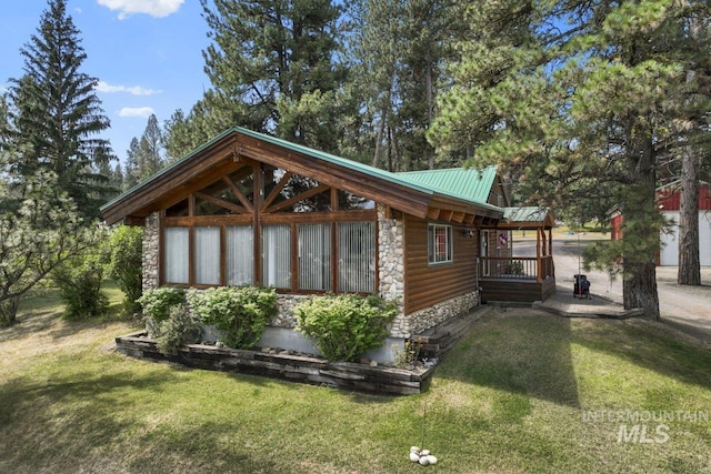 view of side of property featuring faux log siding, a yard, stone siding, and metal roof