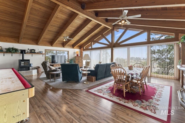 dining room with wood ceiling, ceiling fan, beamed ceiling, and a wood stove