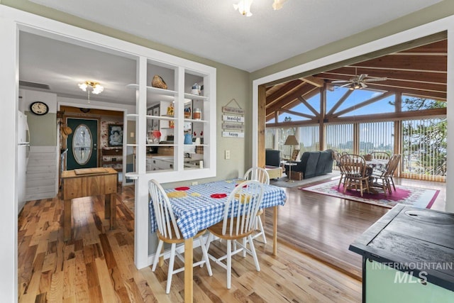 dining room with a ceiling fan, wood finished floors, and lofted ceiling
