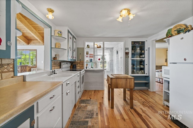 kitchen featuring open shelves, light wood-type flooring, a sink, white appliances, and white cabinetry