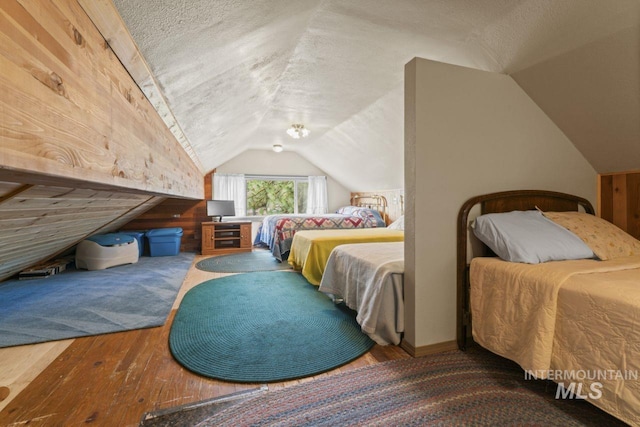 bedroom featuring hardwood / wood-style flooring, a textured ceiling, and lofted ceiling