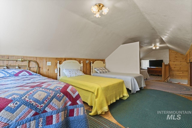 bedroom featuring wooden walls and lofted ceiling