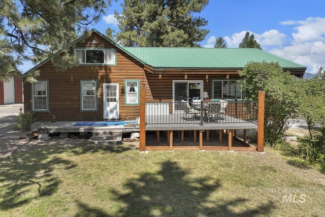 back of house featuring a lawn, metal roof, and a deck