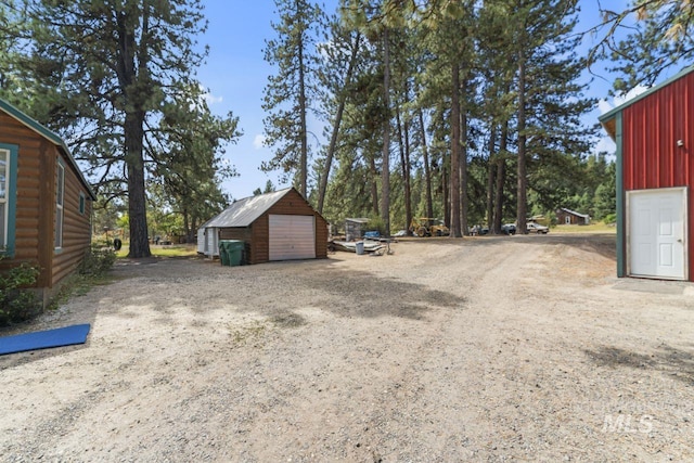 view of yard with a detached garage and an outbuilding