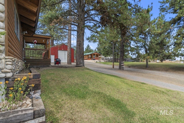 view of yard featuring a detached garage, an outdoor structure, and driveway