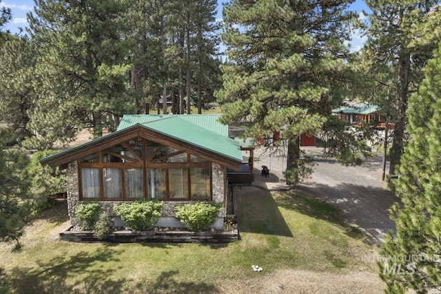 back of house with a lawn, metal roof, and stone siding