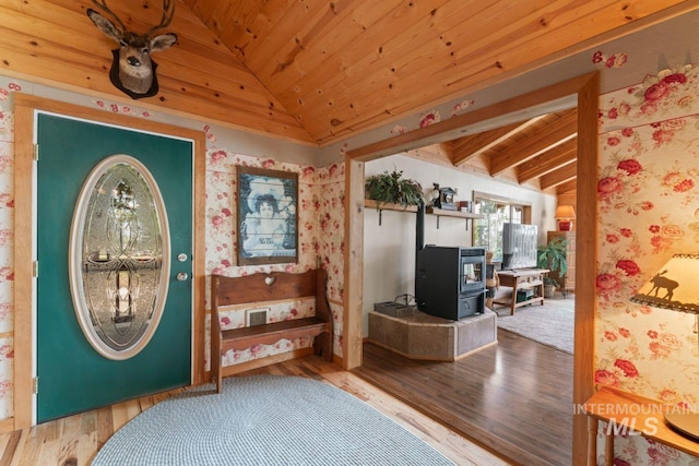 entrance foyer featuring vaulted ceiling, wooden ceiling, wood finished floors, and a wood stove