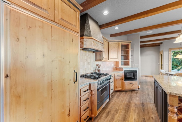 kitchen with custom exhaust hood, high end range, light stone countertops, black microwave, and beam ceiling