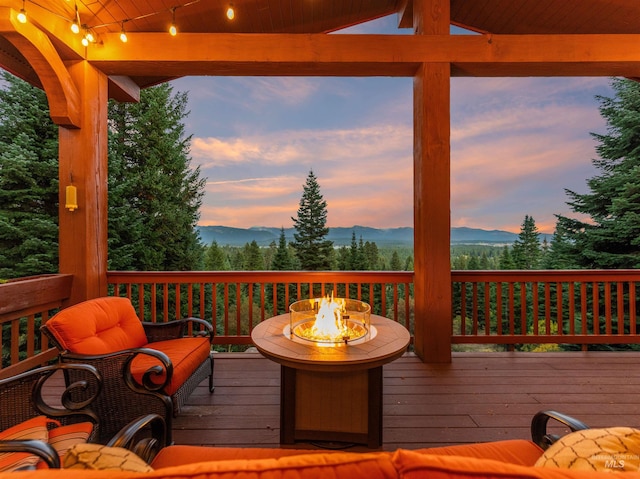 deck at dusk featuring a mountain view and a fire pit