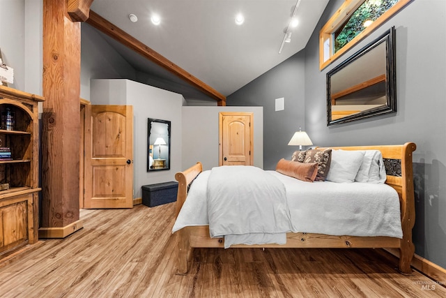 bedroom featuring rail lighting, light hardwood / wood-style floors, and lofted ceiling