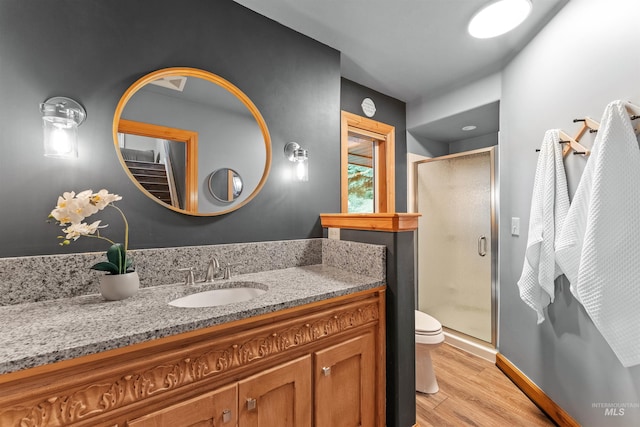 bathroom with wood-type flooring, toilet, walk in shower, and vanity