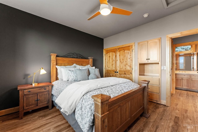 bedroom featuring ceiling fan, vaulted ceiling, ensuite bathroom, and light wood-type flooring