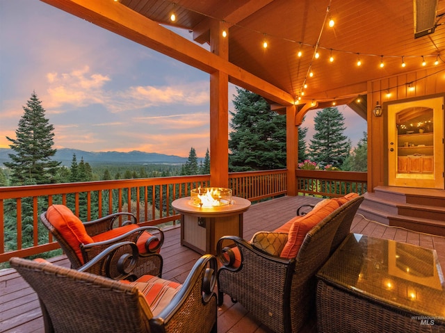 deck at dusk with a fire pit and a mountain view