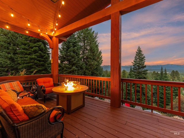 deck at dusk with a mountain view and an outdoor living space with a fire pit