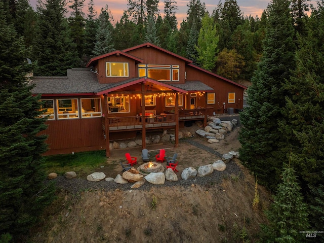 back house at dusk with an outdoor fire pit and a deck