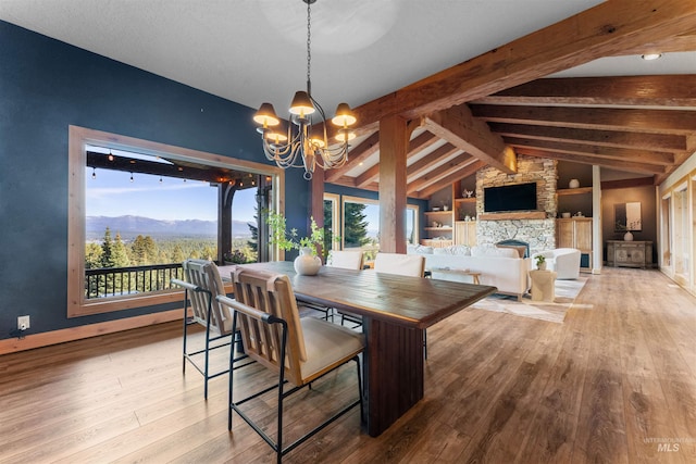 dining room featuring light hardwood / wood-style floors, built in shelves, a fireplace, a mountain view, and an inviting chandelier