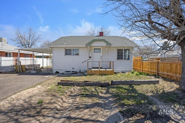 view of front facade featuring a chimney, a carport, fence, and roof with shingles