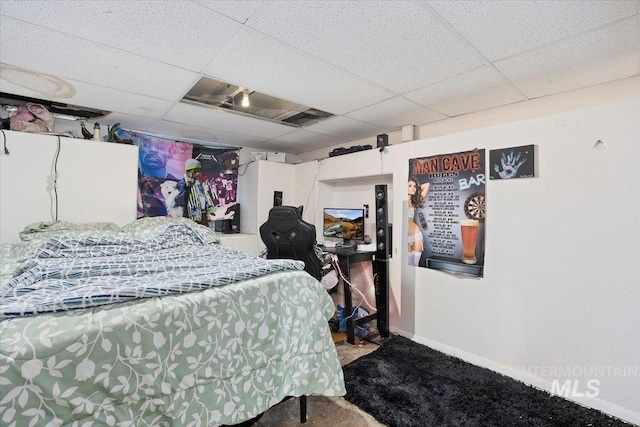 carpeted bedroom with baseboards and a paneled ceiling
