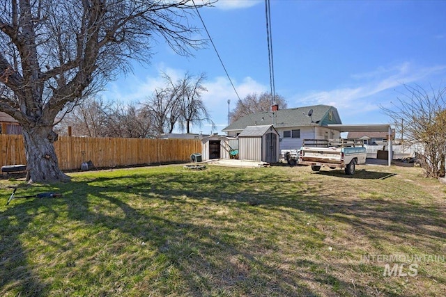 view of yard featuring fence, an outdoor structure, and a storage shed