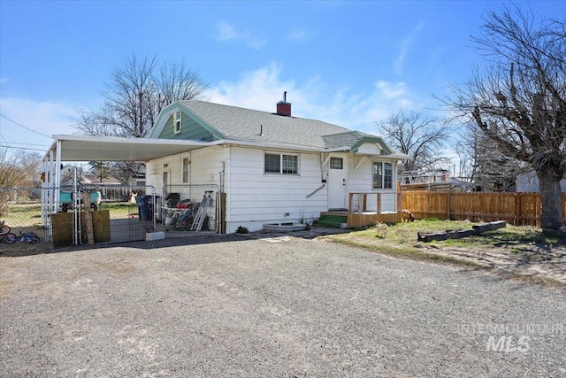 rear view of house with driveway, a chimney, fence, and a carport