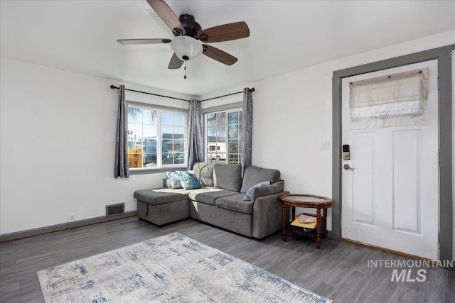living room featuring baseboards, visible vents, wood finished floors, and ceiling fan
