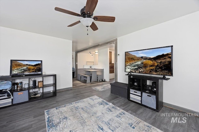 living area with baseboards, ceiling fan, and wood finished floors
